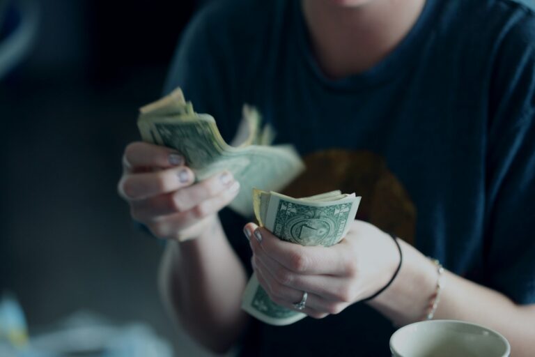 Hands counting dollar bills representing dividend reinvestment and DRIP investing cash flow